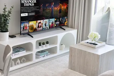 a living room with a tv on a white entertainment center at Cozy Apartment Gym Pool High 17th Floor JVC Gateway to Dubai in Dubai