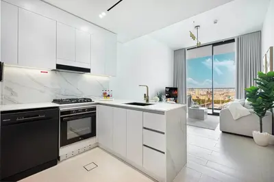a kitchen with white cabinets and a large window at Cozy Apartment Gym Pool High 17th Floor JVC Gateway to Dubai in Dubai