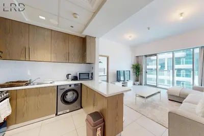 a kitchen and living room with a washer and dryer at Brand New & Modern 1BR Apartment in Dubai