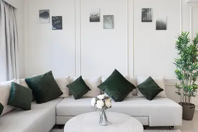 a living room with a white couch with green pillows at SkyHigh 2BR Burj Views Steps to Dubai Mall in Dubai