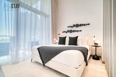 a white bedroom with a bed and a large window at Luxurious Spacious Studio in Dubai