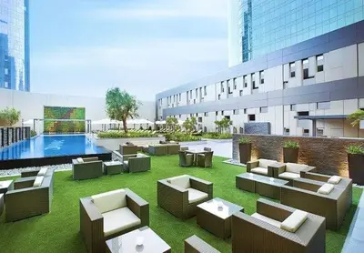 a building with couches and a pool in the grass at DAMAC 1BHK Apt Business Bay Dubai with Pool & Canal Walk in Dubai