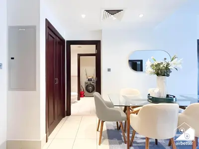 a dining room with a table and white chairs at Burj Views from Balcony l Chic 2BR in Downtown in Dubai
