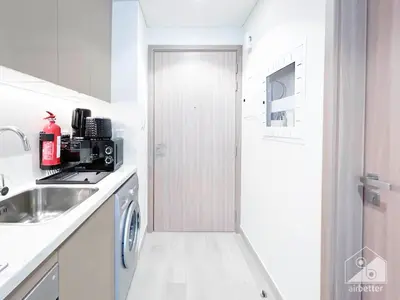 a white kitchen with a sink and a door at Luxury & City Views Studio in Azizi Riviera in Dubai