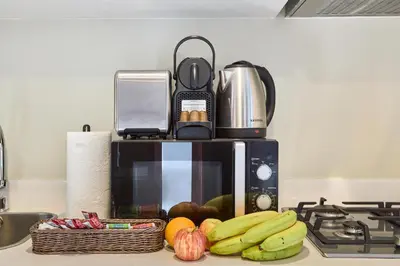 a kitchen counter with a microwave and a basket of fruit at Cozy 1BR Vera Tower with Amazing Burj Khalifa View in Dubai