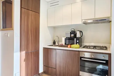 a kitchen with white cabinets and a stove top oven at Cozy 1BR Vera Tower with Amazing Burj Khalifa View in Dubai