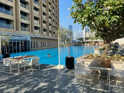 a pool with tables and chairs next to a building at SuperHost EMAAR Residences Fashion Avenue - Former Address Dubai Mall Studio's & 1 BR in Dubai