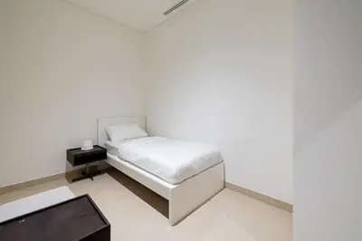 a white bedroom with a bed and a table at Marina Gate 2 Penthouse Iconic Views in Dubai