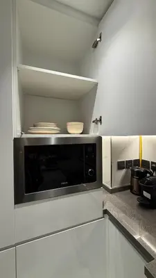 a kitchen with a microwave in a white kitchen at Appartement de Luxe 1 Chambre avec Piscine Privée sur Balcon in Dubai