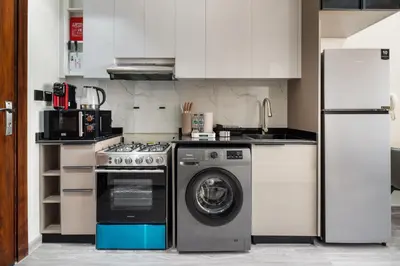 a kitchen with a washing machine and a refrigerator at Stylish Studio Apartment in Binghatti Crystals in Dubai