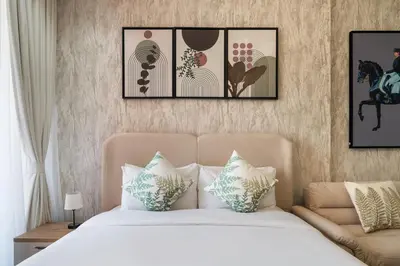 a bedroom with a bed with four pictures on the wall at Stylish Studio Apartment in Binghatti Crystals in Dubai