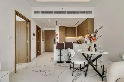 a kitchen and living room with a table and chairs at Elegant 1-Bed with Pool, Gym, Parking and Balcony in Dubai