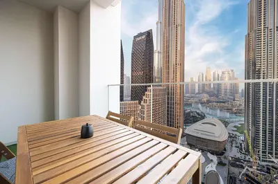 a wooden table on a balcony with a view of a city at Spacious 4-Bedroom Apartment with Full Fountain and Burj Khalifa Views - 10 min Walk to Dubai Mall in Dubai