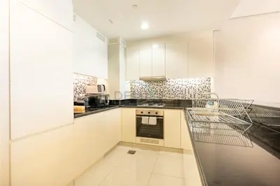 a kitchen with white cabinets and black counter tops at 2BR with Balcony Overlooking City and Burj Khalifa, Minutes Away from Dubai Mall, Paramount Tower Hotel and Residences, Business Bay by Deluxe Holiday Homes in Dubai