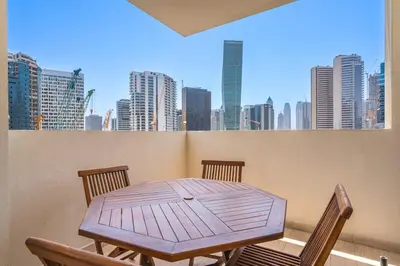 a wooden table and chairs on a balcony with a city skyline at Modern 2BR with Private Terrace, Pool and Gym Access in Dubai
