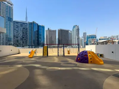 a playground in a city with tall buildings at Modern 2BR with Private Terrace, Pool and Gym Access in Dubai