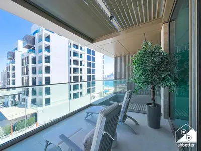 a balcony with two chairs and a potted plant at High End 1BR Palm Beachfront Pool Access in Dubai
