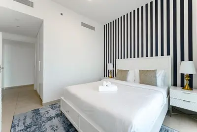 a bedroom with a white bed and a black and white striped wall at Downtown Views II 2 Bedroom with City Skyline and Sea Views in Dubai
