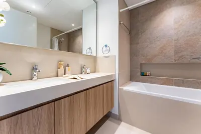 a bathroom with two sinks and a tub and a mirror at Downtown Views II 2 Bedroom with City Skyline and Sea Views in Dubai