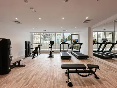 a gym with several treadmills and machines in a room at Elegant 2BR Plus Guest Room Stay with Designer Interior in Dubai