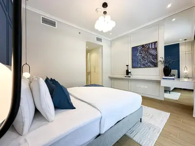 a bedroom with a large white bed and a bathroom at Elegant 2BR Plus Guest Room Stay with Designer Interior in Dubai