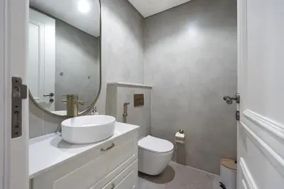 a bathroom with a sink and a toilet and a mirror at Stylish JVC 2BR Stay with Guest Room Rose Gold Accents in Dubai