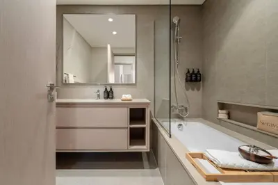 a bathroom with a tub and a sink and a mirror at Seraya at Grande Signature Residences in Dubai