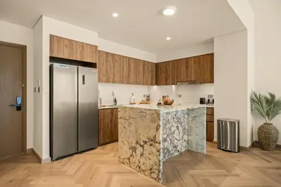 a kitchen with a stainless steel refrigerator and wooden cabinets at Seraya at Grande Signature Residences in Dubai