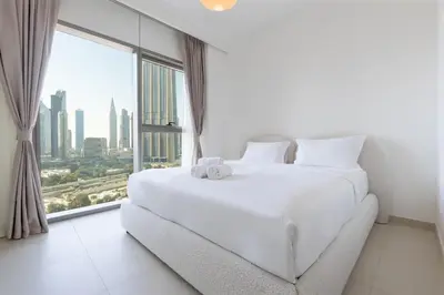 a bedroom with a white bed and a large window at Burj Khalifa Views at Downtown Views II 3 Bedroom Apartment in Dubai