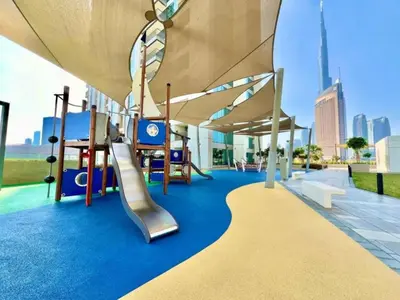 a playground with a slide and swings at Stunning Corner 2 Bedroom in Downtown Views II in Dubai