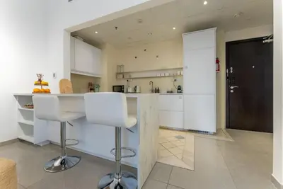 a kitchen with white cabinets and white bar stools at Marina Wharf 1 Bedroom with JBR Beach Views in Dubai