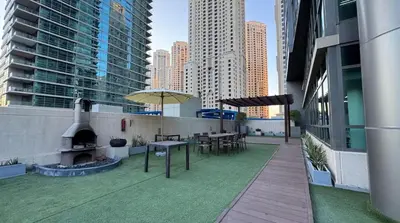 a rooftop patio with a table and an umbrella at Luxury 1BR Dubai Marina Apartment Walk to JBR Beach & Marina Yacht Club in Dubai