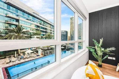 a bedroom with a large window overlooking a pool at Luxury 1BR Dubai Marina Apartment Walk to JBR Beach & Marina Yacht Club in Dubai
