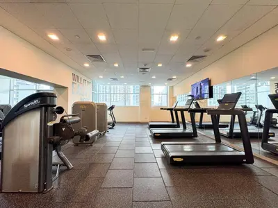 a gym with a row of tread machines and a table at The Lofts, Burj Khalifa View in Dubai