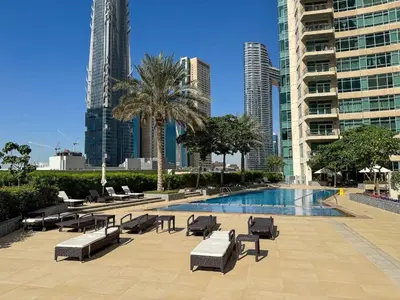 a pool with lounge chairs and a palm tree and buildings at The Lofts, Burj Khalifa View in Dubai