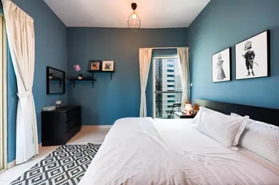 a blue bedroom with a white bed and a window at Best View in Marina Dubai in Dubai