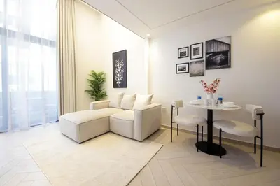 a living room with a table and white chairs at Modern Loft Studio JVC ,Stylish & Fully Furnished in Dubai