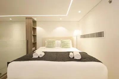 a bedroom with a large white bed with towels on it at Modern Loft Studio JVC ,Stylish & Fully Furnished in Dubai