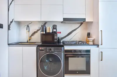 a kitchen with a washing machine and a microwave at Charming Studio with Scenic Canal Views in Dubai