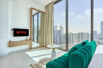 a living room with green chairs and a tv at Charming Studio with Scenic Canal Views in Dubai