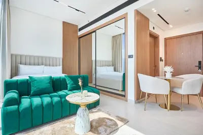 a living room with a green couch and a bed at Charming Studio with Scenic Canal Views in Dubai