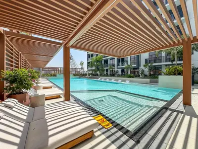 an outdoor swimming pool with a wooden pergola and a swimming poolvisor at Bright Studio in JVC with Pool and Gym Access in Dubai