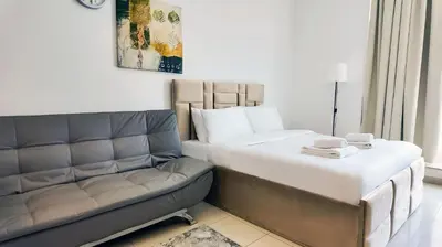 a bedroom with a large bed and a couch at Silk Valley - Cozy Studio steps away from the Beach and Marina in Dubai