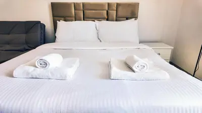 a white bed with towels on top of it at Silk Valley - Cozy Studio steps away from the Beach and Marina in Dubai