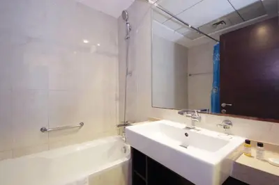 a bathroom with a sink and a tub and a mirror at Silk Valley - Cozy Studio steps away from the Beach and Marina in Dubai