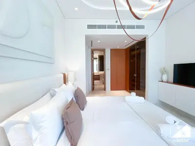 a bedroom with a white bed and a television at Seafront Serenity Palm Escape with Pool Access in Dubai