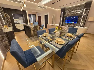 a dining room with a glass table and blue chairs at Highend 2BR Skyline View with Beach JBR in Dubai