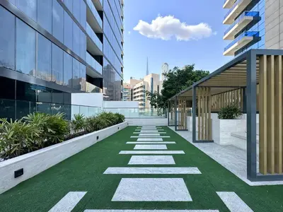 a walkway in a building with green grass at Dubai Studio with Balcony, Canal Views Pool Access in Dubai
