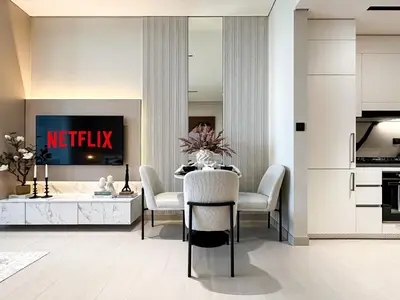 a living room with a table with chairs and a tv at Dubai Studio with Balcony, Canal Views Pool Access in Dubai