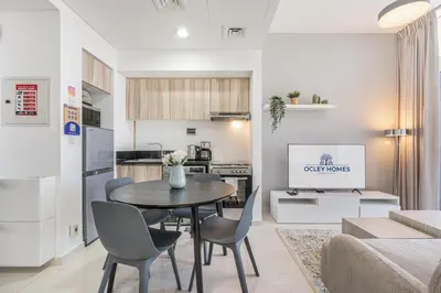 a kitchen and living room with a table and chairs at Contemporary 1BR Home in Damac Hills in Dubai